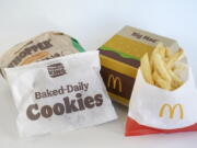 A Burger King Whopper in a wrapper, behind left, and a bag of Burger King cookies, left, rest next to a McDonald's Big Mac in a container, behind right, and a bag of McDonald's fries, in Walpole, Mass., Wednesday, April 20, 2022. Environmental and health groups are pushing dozens of fast food companies, supermarkets chains and other retail outlets to remove PFAS from their packaging.