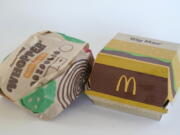 A Burger King Whopper in a wrapper, left, rests next to a McDonald's Big Mac in a container, in Walpole, Mass., Wednesday, April 20, 2022. Environmental and health groups are pushing dozens of fast food companies, supermarket chains and other retail outlets to remove PFAS from their packaging.