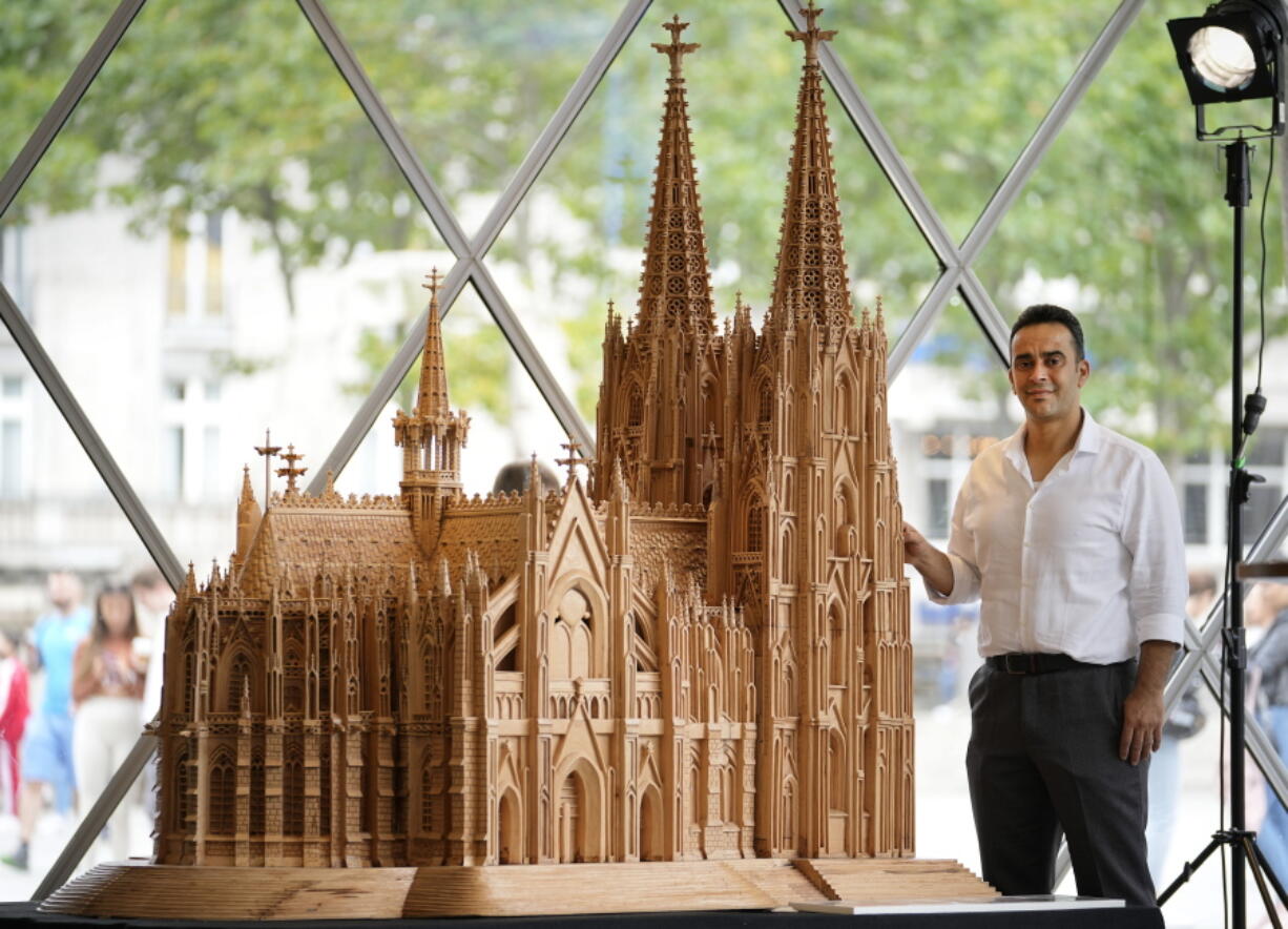 Fadel Alkhudr from Syria poses beside his wooden model of the word heritage Cologne Cathedral on display at the Domforum in Cologne, Germany, Monday, June 20, 2022. Fadel Alkhudr, 42, a woodcarver and artist orginally from Aleppo, Syria, fled the war in his home country and arrived in the western german city of Cologne in 2015. In 2019 he started to carve the local Cologne Cathedral in his small basement - without any plans or drawings, using only cell phone photos of the cathedral as a template.