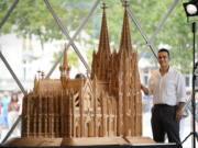 Fadel Alkhudr from Syria poses beside his wooden model of the word heritage Cologne Cathedral on display at the Domforum in Cologne, Germany, Monday, June 20, 2022. Fadel Alkhudr, 42, a woodcarver and artist orginally from Aleppo, Syria, fled the war in his home country and arrived in the western german city of Cologne in 2015. In 2019 he started to carve the local Cologne Cathedral in his small basement - without any plans or drawings, using only cell phone photos of the cathedral as a template.