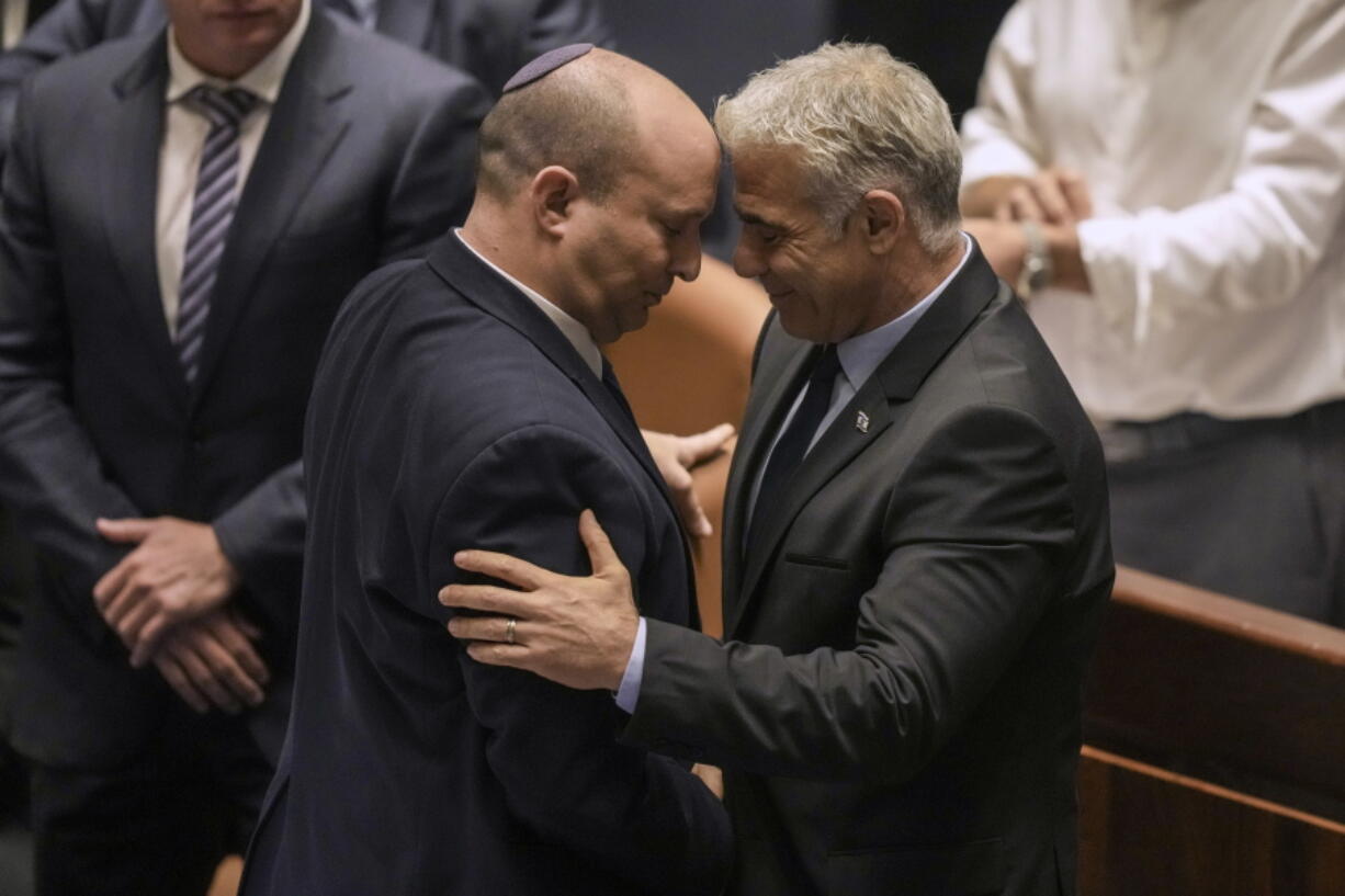 Israeli Prime Minister Naftali Bennett, left, and Foreign Minister Yair Lapid react after a vote on a bill to dissolve the parliament at the Knesset, Israel's parliament, in Jerusalem, Thursday, June 30, 2022. Israel's parliament has voted to dissolve itself, sending the country to the polls for the fifth time in less than four years.