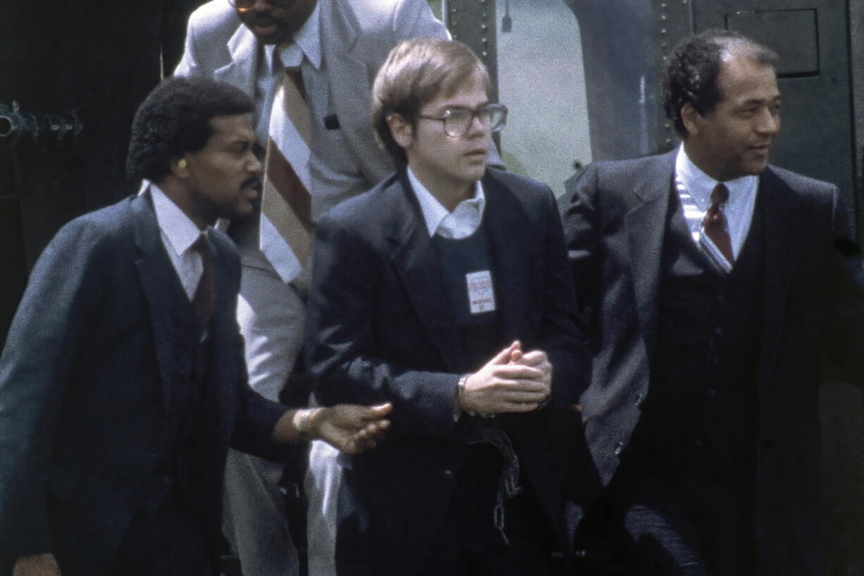 FILE - U.S. Marshals escort John Hinckley Jr. as he returns to a marine base via helicopter in Quantico, Va., Aug. 8, 1981. Hinckley, who shot and wounded President Ronald Reagan in 1981, was freed from court oversight Wednesday, June 15, 2022, officially concluding decades of supervision by legal and mental health professionals.