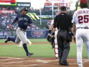 Seattle Mariners Julio Rodriguez, left, scores on a single by Eugenio Suarez as Los Angeles Angels starting pitcher Michael Lorenzen, right, watches along with home plate umpire Will Little during the first inning of a baseball game Friday, June 24, 2022, in Anaheim, Calif. (AP Photo/Mark J.