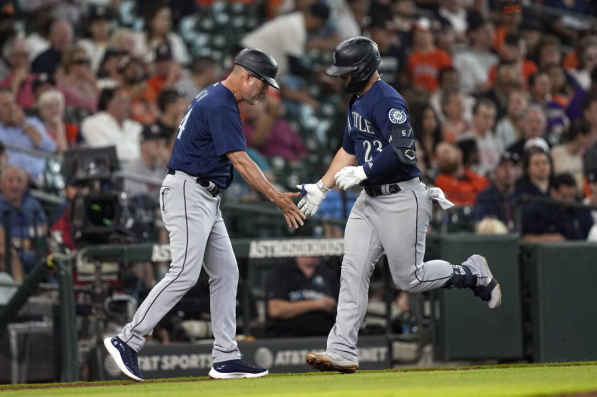 Seattle Mariners' Ty France (23) celebrates with third base coach Manny Acta after hitting a home run against the Houston Astros during the fourth inning of a baseball game Wednesday, June 8, 2022, in Houston. (AP Photo/David J.