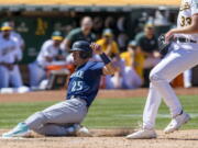 Seattle Mariners' Dylan Moore (25) scores on a wild pitch by Oakland Athletics' A.J. Puk (33) during the ninth inning of a baseball game in Oakland, Calif., Thursday, June 23, 2022.