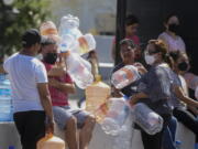 Neighbors wait with plastic containers in hand to collect water at a public collection point in Monterrey, Mexico, Monday, June 20, 2022. Local authorities began restricting water supplies in March, as a combination of an intense drought, poor planning and high use has left the three dams that help supply the city dried up, with thousands of homes not receiving any water for weeks.