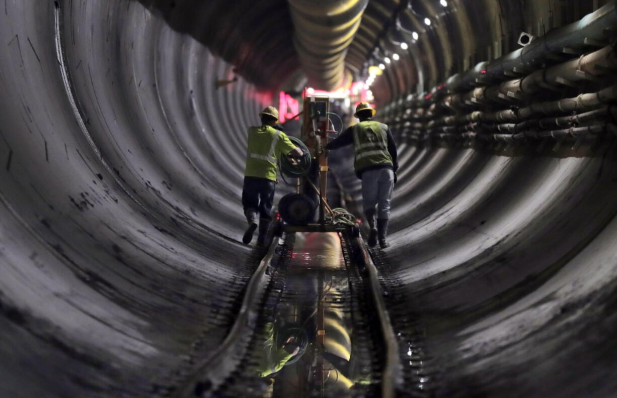 FILE - Tunnel workers push equipment up a rail track to a machine boring a 2.5-mile bypass tunnel for the Delaware Aqueduct in Marlboro, N.Y., on May 16, 2018. A long-planned temporary shutdown of a leaking aqueduct that supplies about half of New York City's drinking water will be pushed back a year, giving officials more time to prepare for the months-long closure.