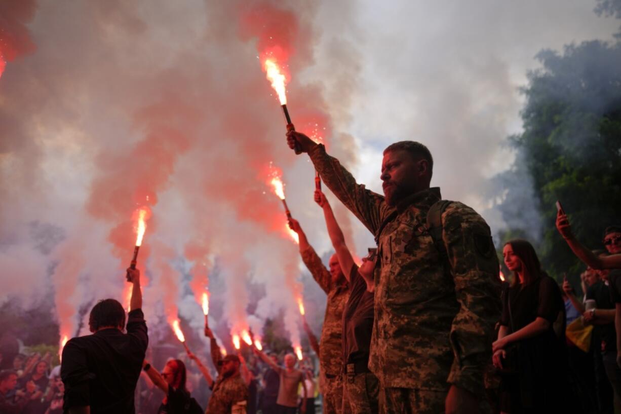 Soldiers hold flares as they attend the funeral of activist and soldier Roman Ratushnyi in Kyiv, Ukraine, Saturday, June 18, 2022. Ratushnyi died in a battle near Izyum, where Russian and Ukrainian troops are fighting for control of the area.