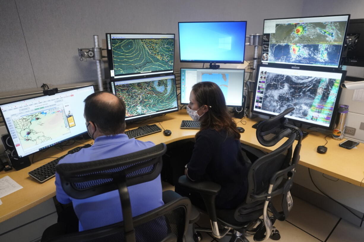 Senior hurricane specialist Daniel Brown, left, and hurricane specialist Lisa Bucci track the remnants of Hurricane Agatha on Wednesday at the National Hurricane Center in Miami.