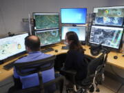 Senior hurricane specialist Daniel Brown, left, and hurricane specialist Lisa Bucci track the remnants of Hurricane Agatha on Wednesday at the National Hurricane Center in Miami.