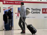 FILE - Passengers get a COVID-19 test at Heathrow Airport in London, Nov. 29, 2021.  The Biden administration is lifting its requirement that international air travelers to the U.S. take a COVID-19 test within a day before boarding their flights, easing one of the last remaining government mandates meant to contain the spread of the coronavirus. A senior administration official says the mandate expires Sunday at 12:01 a.m. Eastern time. The official says the Centers for Disease Control and Prevention has determined that it's no longer necessary.