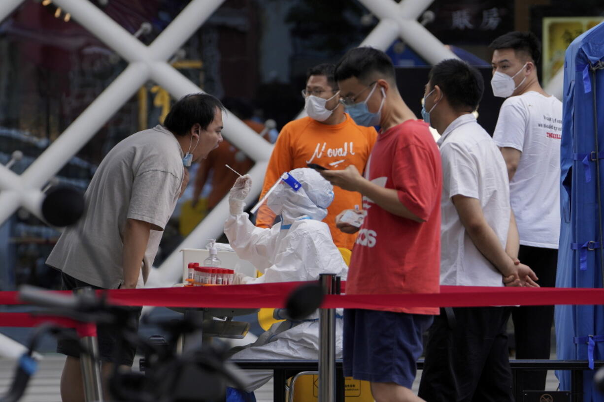 Residents get swabbed during mass COVID-19 testing in the Chaoyang district in Beijing, Tuesday, June 14, 2022. Authorities ordered another round of three days of mass testing for residents in the Chaoyang district following the detection of hundreds coronavirus cases linked to a nightclub.