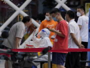 Residents get swabbed during mass COVID-19 testing in the Chaoyang district in Beijing, Tuesday, June 14, 2022. Authorities ordered another round of three days of mass testing for residents in the Chaoyang district following the detection of hundreds coronavirus cases linked to a nightclub.