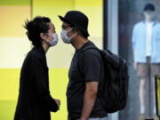 A couple wearing face masks move in closer to kiss as they line up for their COVID-19 tests at a testing facility near a shopping mall where most shops have ordered to closed as part of COVID-19 controls in Beijing, Monday, June 13, 2022. China's capital has put school online in one of its major districts amid a new COVID-19 outbreak linked to a nightclub, while life has yet to return to normal in Shanghai despite the lifting of a more than two month-long lockdown.