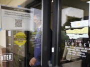 Washington Gov. Jay Inslee walks past a sign asking visitors to complete a health screening as he steps outside to talk to reporters, Thursday, June 2, 2022, at a Dept. of Ecology office in Richland, Wash. On May 25, 2022, Inslee's office said the Governor had tested positive for COVID-19. Inslee, who has recently criticized the slow pace of cleaning up the Hanford Nuclear Reservation in Washington state, was speaking ahead of a scheduled tour of the nuclear weapons production site and repeated his message that more federal money is needed to finish the job. (AP Photo/Ted S.