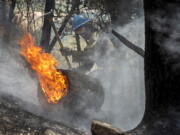 FILE - Carson Hot Shots Tyler Freeman works to keep a burning log from rolling down a slope, May 23, 2022, as he and his co-workers work on hot spots from the Calf Canyon/Hermits Peak Fire in the Carson National Forest west of Chacon, N.M. The U.S. Forest Service is acknowledging multiple miscalculations, inaccurate models and a lack of understanding of just how dry things are in the Southwest in a review of a planned burn that turned into the largest blaze in New Mexico's recorded history. The agency on Tuesday, June 21, 2022, released the findings after investigating the decisions that led up to igniting a prescribed fire that was meant to remove vegetation in an effort to reduce the wildfire threat in the Sangre de Cristo mountain range in northern New Mexico.