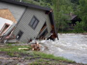 A house that was pulled into Rock Creek in Red Lodge, Mont., by raging floodwaters is seen Tuesday, June 14, 2022. Officials said more than 100 houses in the small city were flooded when torrential rains swelled waterways across the Yellowstone region.