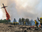 Wildland firefighters watch and take video with their cellphones as a plane drops fire retardant on Harlow Ridge above the Lick Creek Fire, southwest of Asotin, Wash., Monday, July 12, 2021. The fire, which started last Wednesday, has now burned over 50,000 acres of land between Asotin County and Garfield County in southeast Washington state.