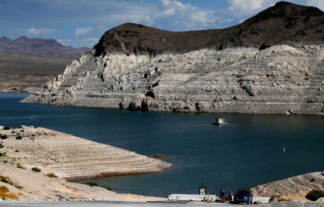 Kayakers taking their gear out of the water are dwarfed by a white bathtub ring around Echo Bay in Lake Mead.