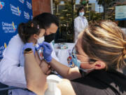 Sofia Espinoza Tam is held by her father, Children's Hospital Los Angeles pediatrician Dr. Juan Espinoza, while nurse Monica Lopez administers the Pfizer COVID-19 vaccine on June 21.