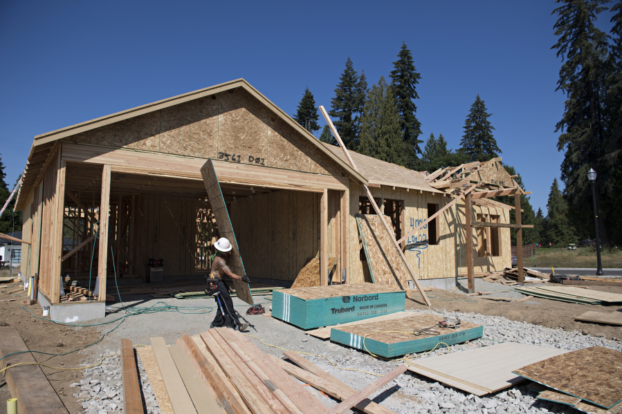 Construction workers lend a hand building homes at the Cedars community in Brush Prairie in July.