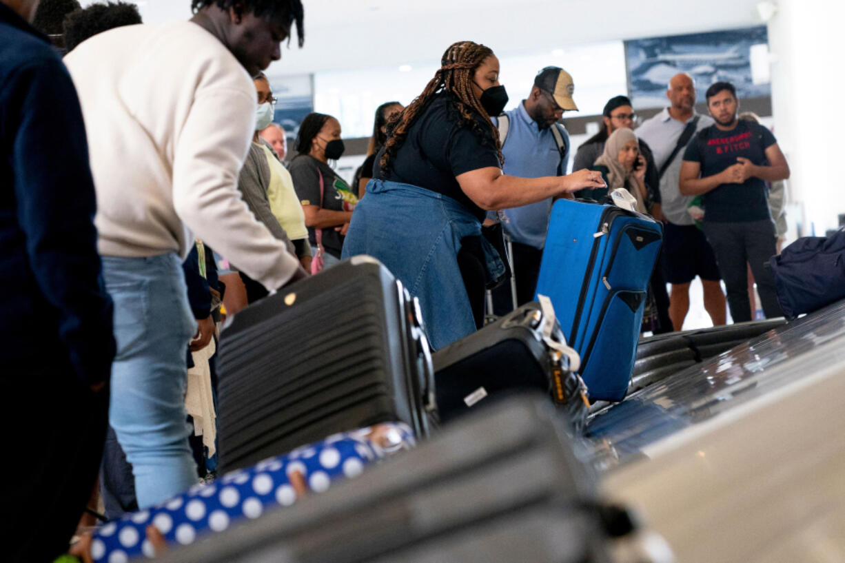 Travelers pick up their baggage while arriving July 2 at Ronald Reagan Washington National Airport in Arlington, Va.