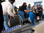 Travelers pick up their baggage while arriving July 2 at Ronald Reagan Washington National Airport in Arlington, Va.