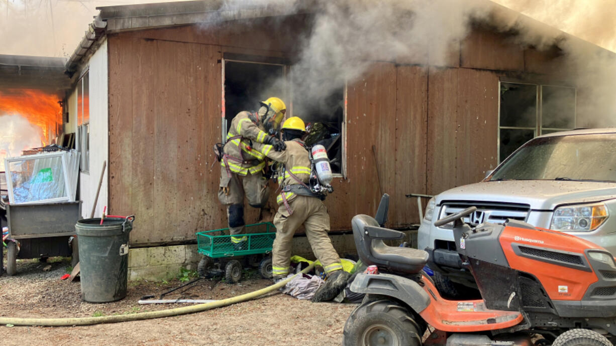 Clark-Cowlitz firefighters extinguish a fire that destroyed a manufactured home north of Lewisville Park Thursday.