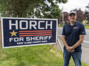 Clark County sheriff candidate John Horch stands next to a campaign sign on Northwest 139th Street in Salmon Creek.