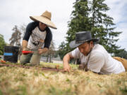 Portland State University student Joshua Haupt, left, scoops dirt into a bucket while Portland State University student Patty Patterson digs in the ground Tuesday during Archaeology Field School at Fort Vancouver National Historic Site.