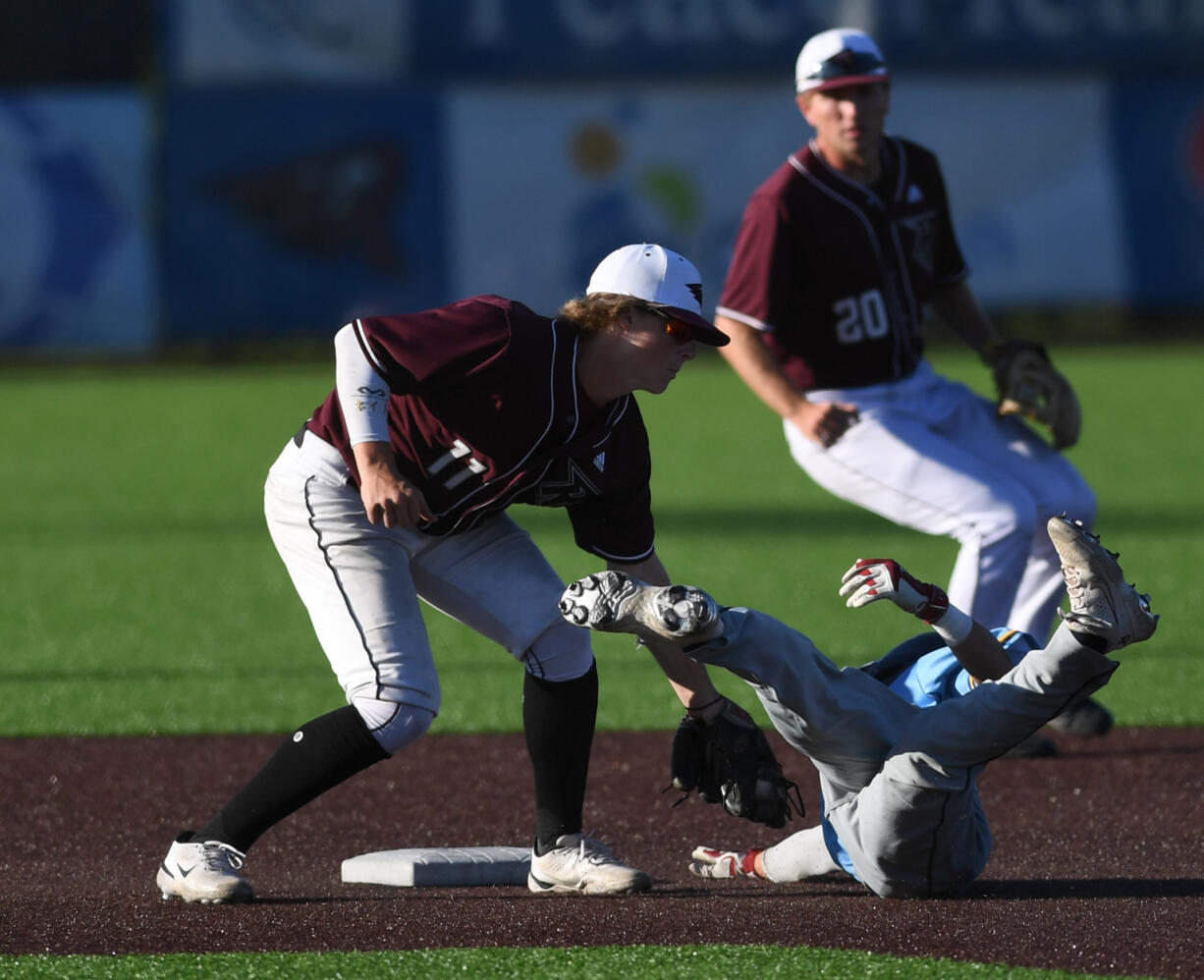 Raptors second baseman Nate Kirkpatrick tags out a tumbling Bellingham baserunner Tuesday, July 12, 2022, during a game between the Ridgefield Raptors and the Bellingham Bells at the Ridgefield Outdoor Recreation Complex.