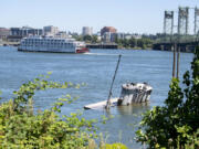 An abandoned ship, foreground, is seen in the Columbia River near Jantzen Beach, Ore., as the American Pride riverboat cruises past Vancouver.