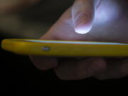 In this Sunday, Aug. 11, 2019, photo, a man uses a cell phone in New Orleans. Quick help for suicidal thoughts and other mental health emergencies may soon be as easy as 9-8-8. The United States' first nationwide three-digit mental health crisis hotline goes live on Saturday, July 16, 2022.