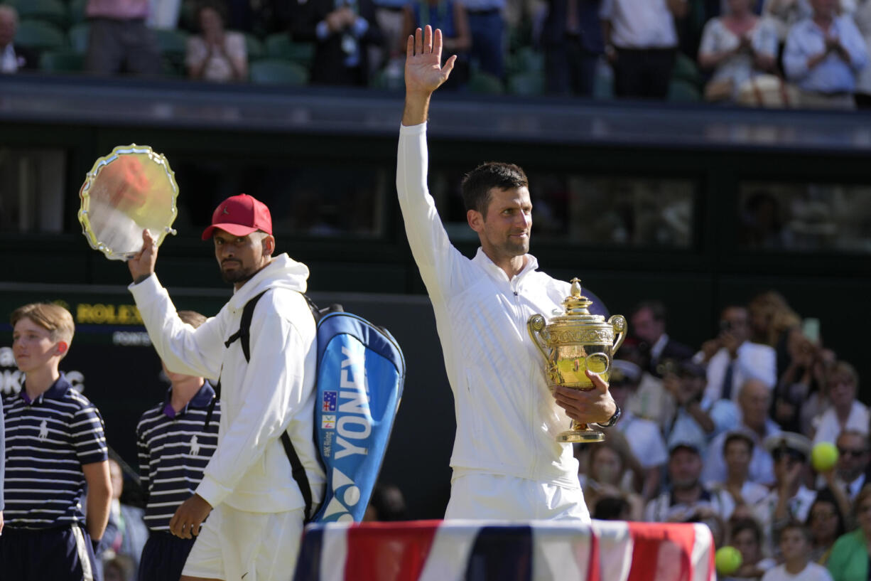 Serbia's Novak Djokovic, right, holds the winners trophy as he celebrates after beating Australia's Nick Kyrgios, left, to win the final of the men's singles on day fourteen of the Wimbledon tennis championships in London, Sunday, July 10, 2022.