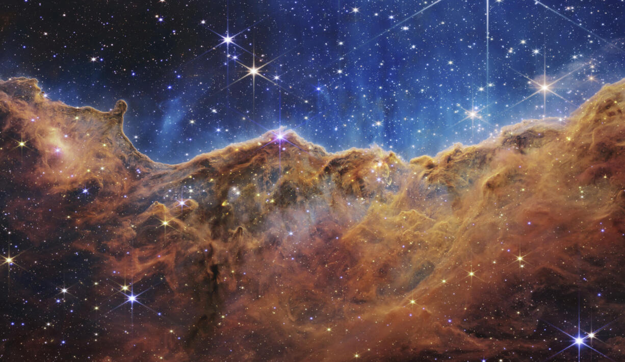 This image released by NASA on Tuesday, July 12, 2022, shows the edge of a nearby, young, star-forming region NGC 3324 in the Carina Nebula. Captured in infrared light by the Near-Infrared Camera (NIRCam) on the James Webb Space Telescope, this image reveals previously obscured areas of star birth, according to NASA.