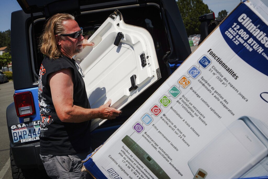 Brian Gadzuk, 56, clears out the trunk of his Jeep to make space for a new air conditioning unit in the parking lot of McLendon Hardware in Renton, Wash., on Sunday, July 24, 2022. The Pacific Northwest is bracing for a major heat wave, with temperatures forecast to top 100 degrees Fahrenheit (37.8 Celsius) in some places this week as climate change fuels longer hot spells in a region where such events were historically uncommon.