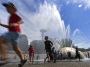 The International Fountain at Seattle Center is packed with children as they run from the water that is showering on them Wednesday, July 27, 2022 in Seattle. (Ellen M.