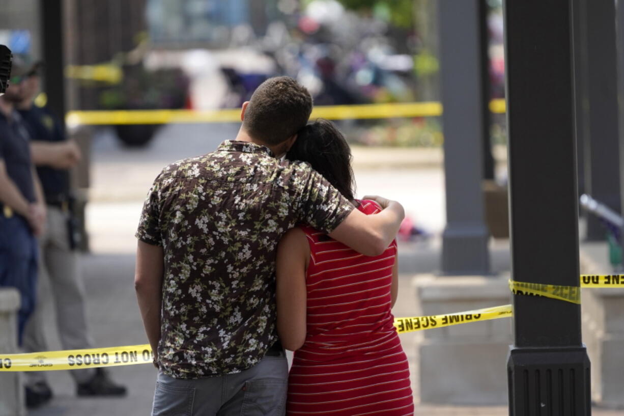 Brooke and Matt Strauss, who were married Sunday, look toward the scene of the mass shooting in downtown Highland Park, Ill., a Chicago suburb, after leaving their wedding bouquets near the scene of Monday's mass shooting, Tuesday, July 5, 2022.