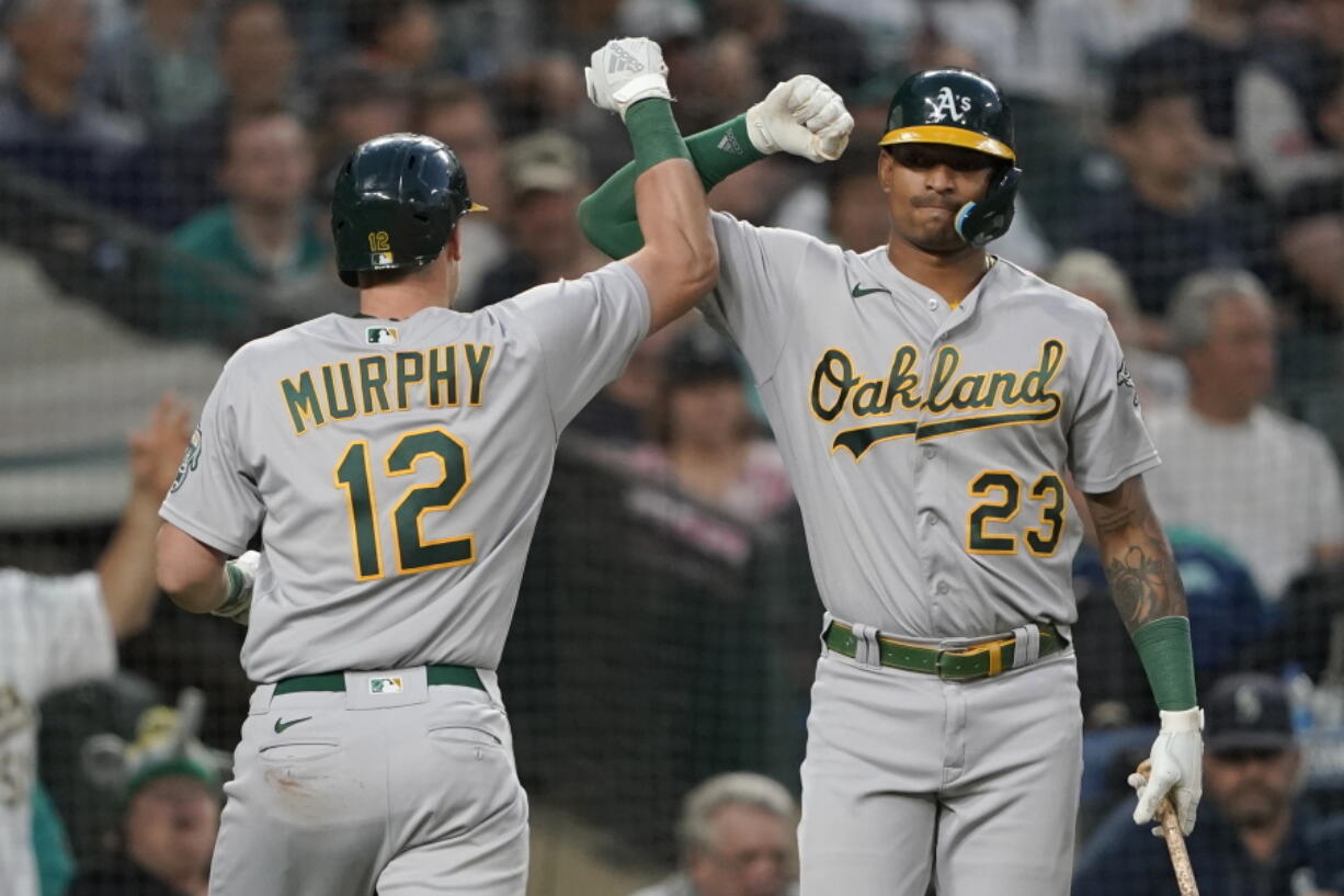 Oakland Athletics' Sean Murphy (12) is congratulated by Christian Bethancourt (23) after Murphy hit a solo home run against the Seattle Mariners during the seventh inning of a baseball game Friday, July 1, 2022, in Seattle. (AP Photo/Ted S.