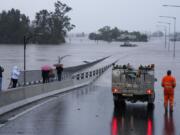 An emergency vehicle blocks access to the flooded Windsor Bridge on the outskirts of Sydney, Australia, Monday, July 4, 2022. More than 30,000 residents of Sydney and its surrounds have been told to evacuate or prepare to abandon their homes on Monday as Australia's largest city braces for what could be its worst flooding in 18 months.