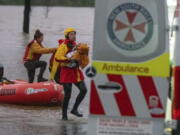 In this photo provided by the State Emergency Service, surf lifesaver Lee Archer carries a baby as the child and the mother are rescued from flood waters in Bulga, Australia, Wednesday, July, 6, 2022. Floodwaters were receding in Sydney and its surrounds on Thursday, July 7, 2022, as heavy rain continued to threaten to inundate towns north of Australia's largest city.