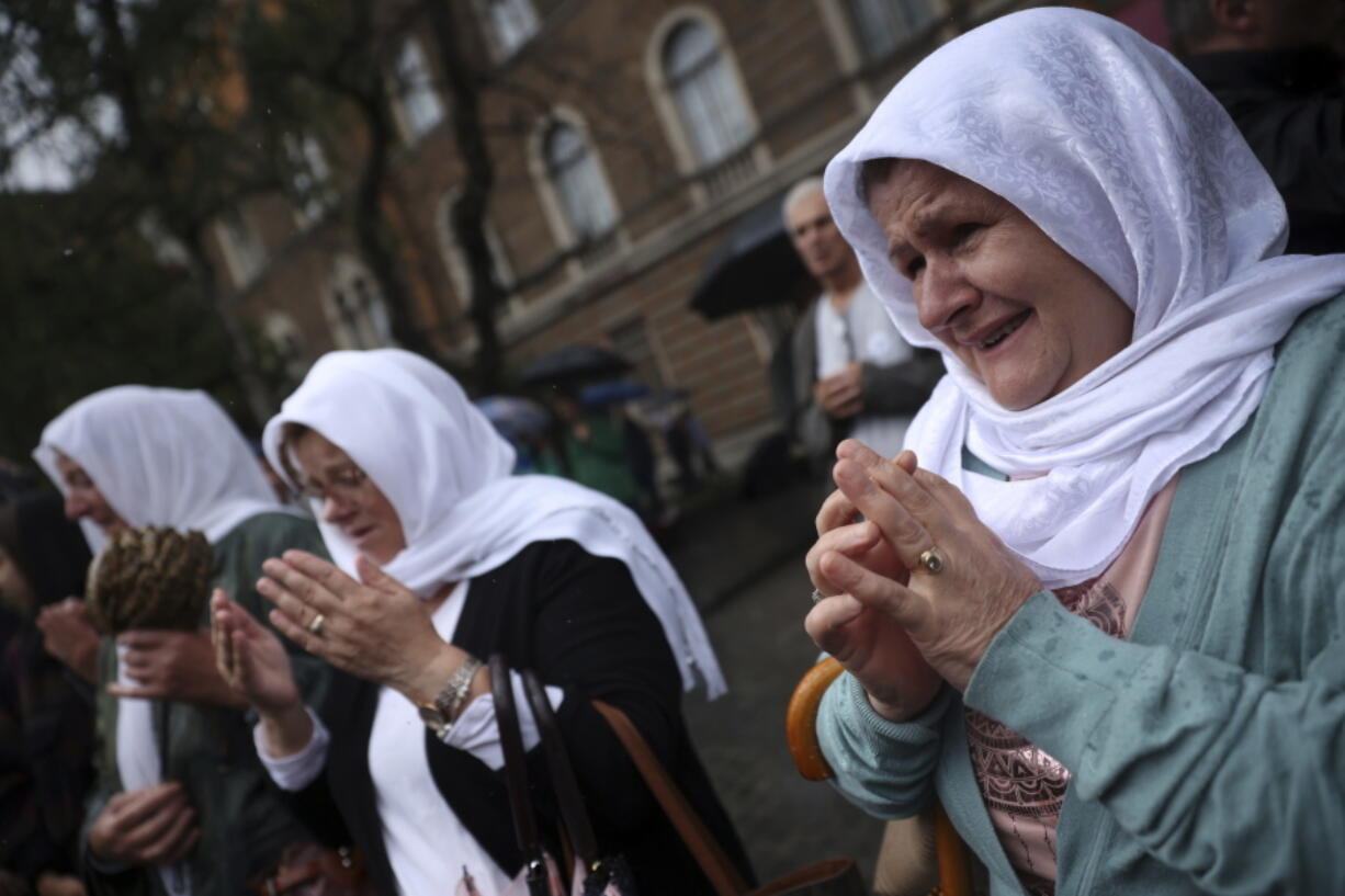 Women pray next to the truck carrying 50 coffins with remains of the victims of the 1995 Srebrenica genocide in Sarajevo, Bosnia, Friday, July 8, 2022. The remains of the 50 recently identified victims of Srebrenica Genocide will be transported to the Memorial centre in Potocari where they will be buried on July 11, the anniversary of the Genocide.