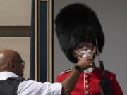 A police officer givers water to a British soldier wearing a traditional bearskin hat, on guard duty outside Buckingham Palace, during hot weather in London, Monday, July 18, 2022. The British government have issued their first-ever "red" warning for extreme heat. The alert covers large parts of England on Monday and Tuesday, when temperatures may reach 40 degrees Celsius (104 Fahrenheit) for the first time, posing a risk of serious illness and even death among healthy people, the U.K. Met Office, the country's weather service, said Friday.