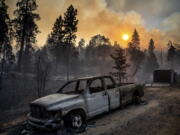 The Oak Fire burns behind a scorched pickup truck in the Jerseydale community of Mariposa County, Calif., early Sunday, July 24, 2022.