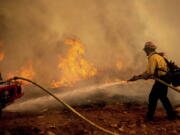 A firefighter sprays water while trying to keep the Electra Fire from spreading in the Pine Acres community of Amador County, Calif., on Tuesday, July 5, 2022.