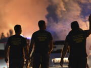 Firefighters watch a wildfire burning near Zaton, Croatia, Wednesday, July 13, 2022. Fueled by strong winds, fires raged at Croatia's Adriatic Sea, with the most dramatic situation reported near the town of Sibenik, where water-dropping planes and dozens of firefighters struggled to contain the flames that briefly engulfed some cars and the church tower in the Zaton area on the outskirts of the town before firefighters managed to put it out.