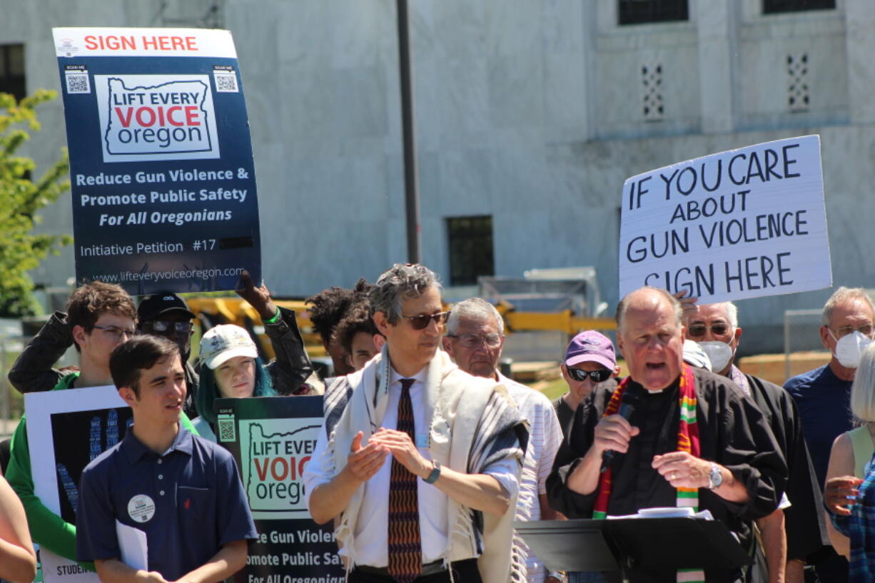 FILE -Rev. Mark Knutson, right, chief petitioner of a gun initiative, speaks at a rally, joined by Rabbi Michael Cahana, center, outside the Oregon State Capitol in Salem before signatures are delivered to Oregon elections officials to get the proposal on the ballot on July 8, 2022. Oregonians will decide in November whether people wanting to purchase a gun will first have to qualify for a permit, after one of the strictest gun-control measures in the nation was approved to get on the ballot.