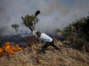 FILE - A local resident fights a forest fire with a shovel during a wildfire in Tabara, north-west Spain, July 19, 2022. Major wildfires in Europe are starting earlier in the year, becoming more frequent, doing more damage and getting harder to stop. And, scientists say, they're probably going to get worse as climate change intensifies unless countermeasures are taken.