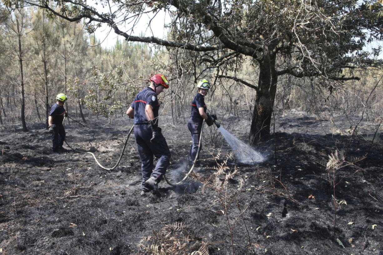 A firefighter sprays water at a burnt forest in Hostens, southwest France, Thursday, July 21, 2022. Officials said, the fires in southwest France are increasingly under control.