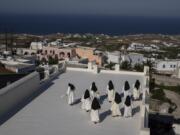 Cloistered nuns walk on a terrace of the Catholic Monastery of St. Catherine on the Greek island of Santorini on Tuesday, June 14, 2022. Twice a day, the nuns recess to chat on the convent's wide terraces, the Aegean Sea shimmering in the distance.